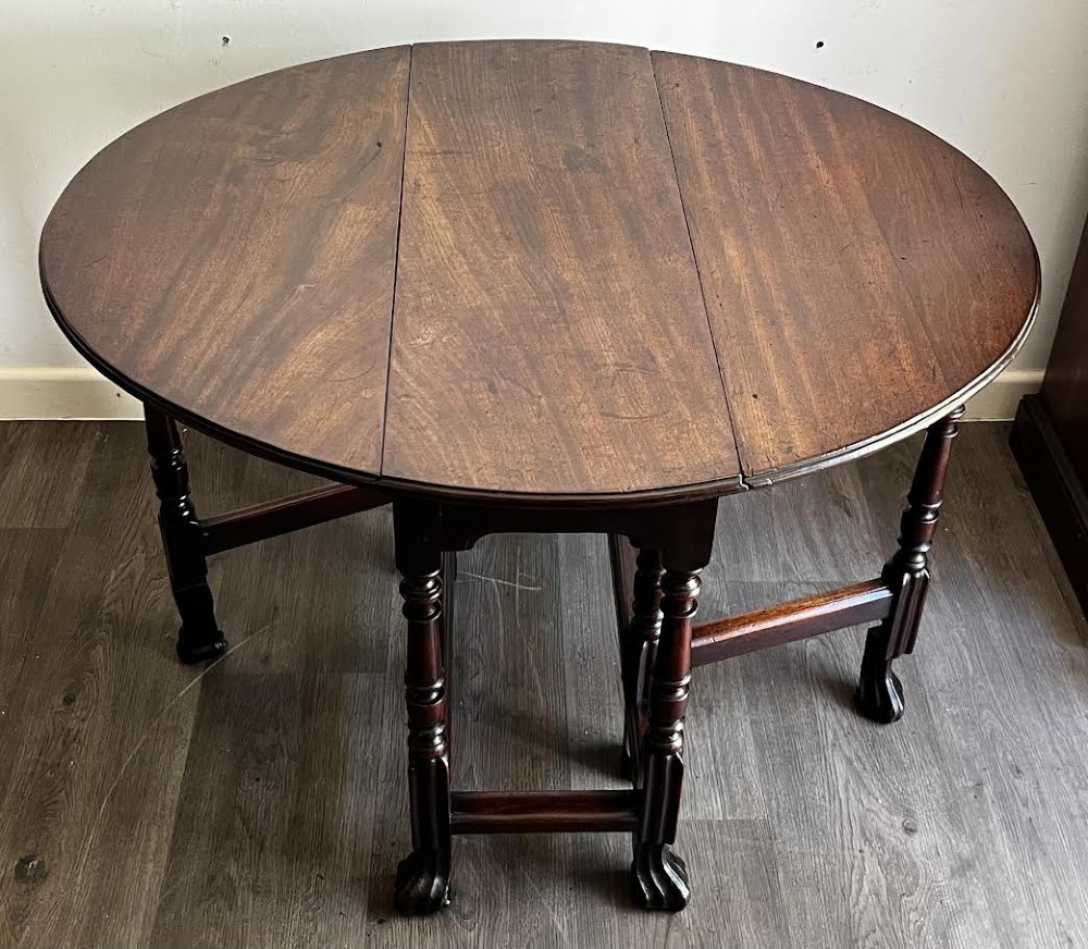 A dark mahogany Georgian drop flap dining table with turned gatelegs and feet.