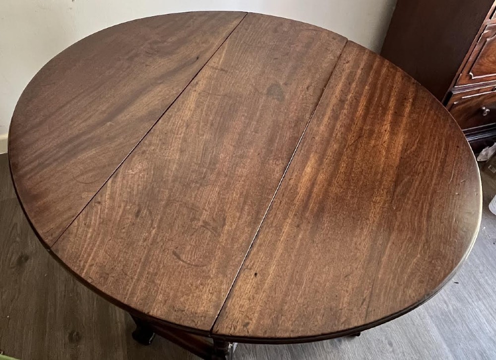 A dark mahogany Georgian drop flap dining table with turned gatelegs and feet. View V