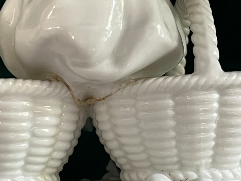 A pair of white glazed porcelain figurines depicting a male and female figure in 18th-century attire, each seated between two woven basket-form dishes on scrollwork bases. View VI