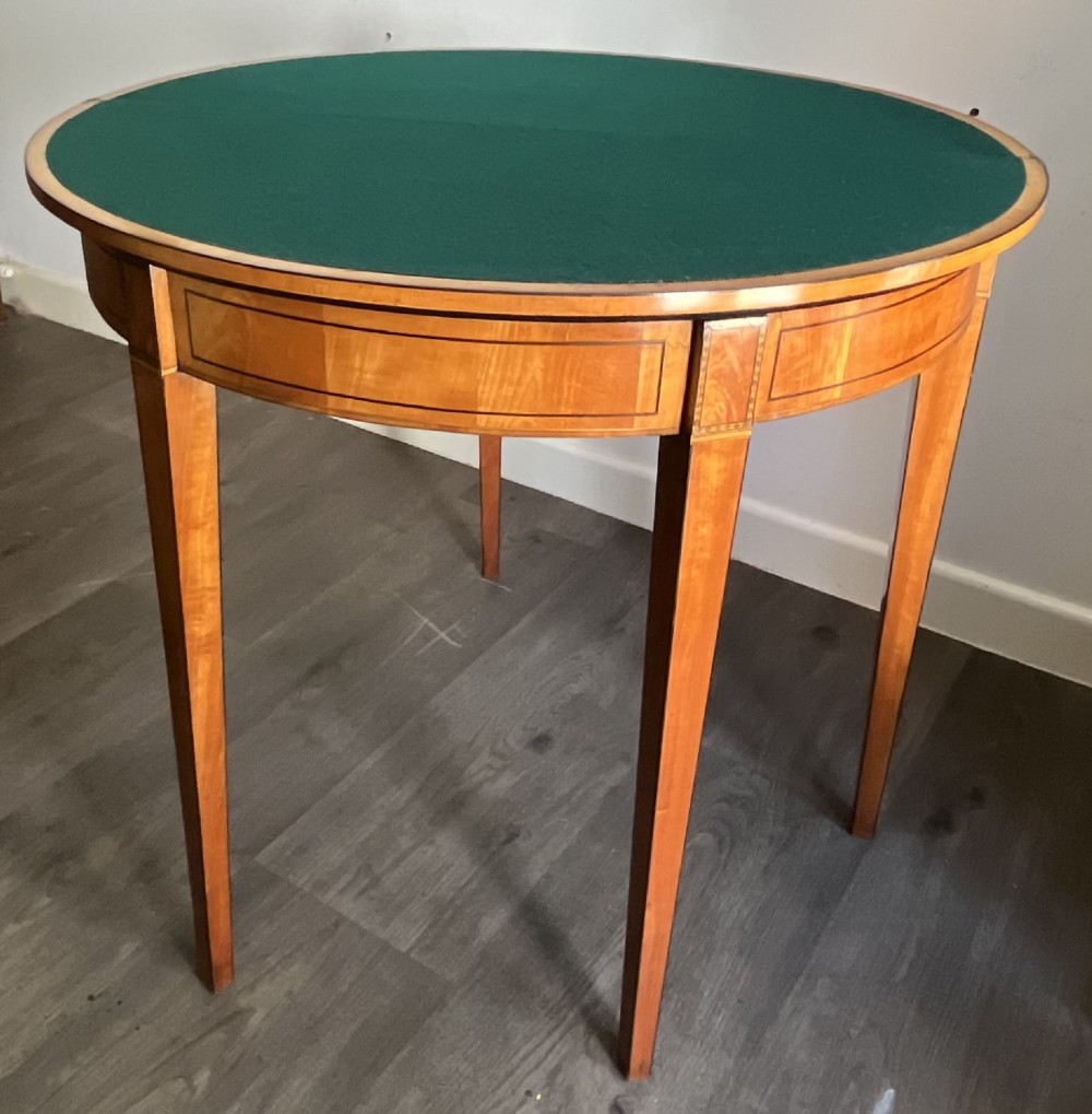 An antique George III demilune card table in honey satinwood featuring geometric parquetry inlay and tapered legs. View III