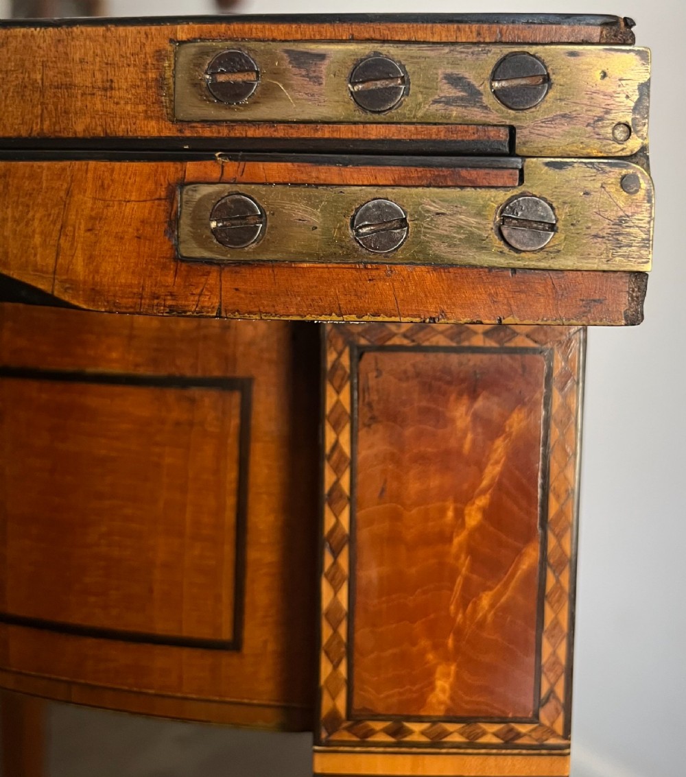 An antique George III demilune card table in honey satinwood featuring geometric parquetry inlay and tapered legs. View IV