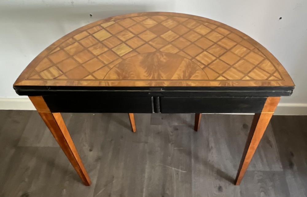 An antique George III demilune card table in honey satinwood featuring geometric parquetry inlay and tapered legs. View VIII