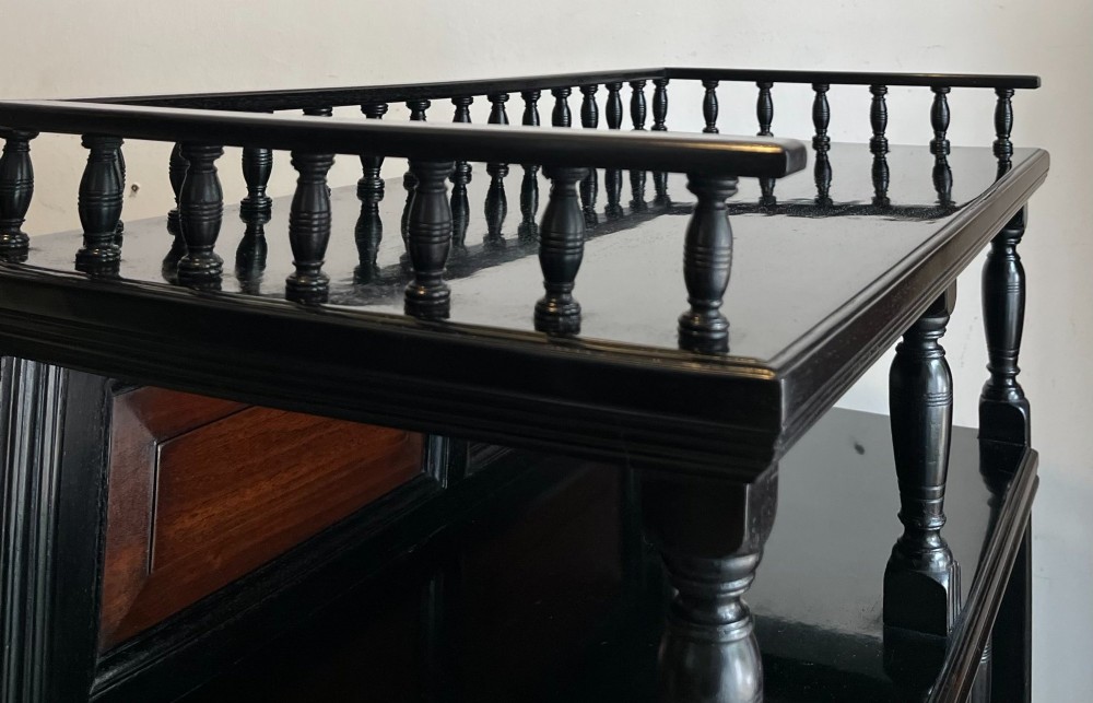 A late Victorian ebonised wood cabinet with a top spindle gallery, dark mahogany panels, and a central door featuring a profile ceramic tile of Dante. View III