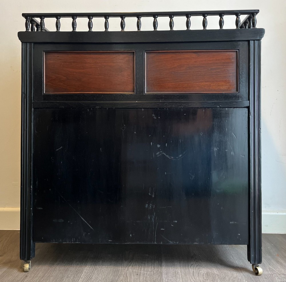 A late Victorian ebonised wood cabinet with a top spindle gallery, dark mahogany panels, and a central door featuring a profile ceramic tile of Dante. View V