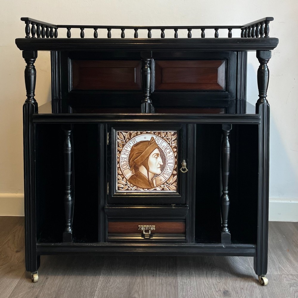 A late Victorian ebonised wood cabinet with a top spindle gallery, dark mahogany panels, and a central door featuring a profile ceramic tile of Dante. View VIII