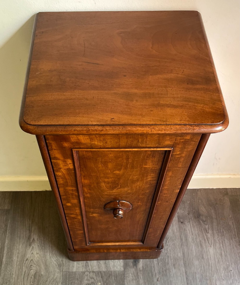 A Victorian warm brown timber pot cupboard featuring a single fielded panel door with a carved central wooden knob and a sturdy plinth base. View II