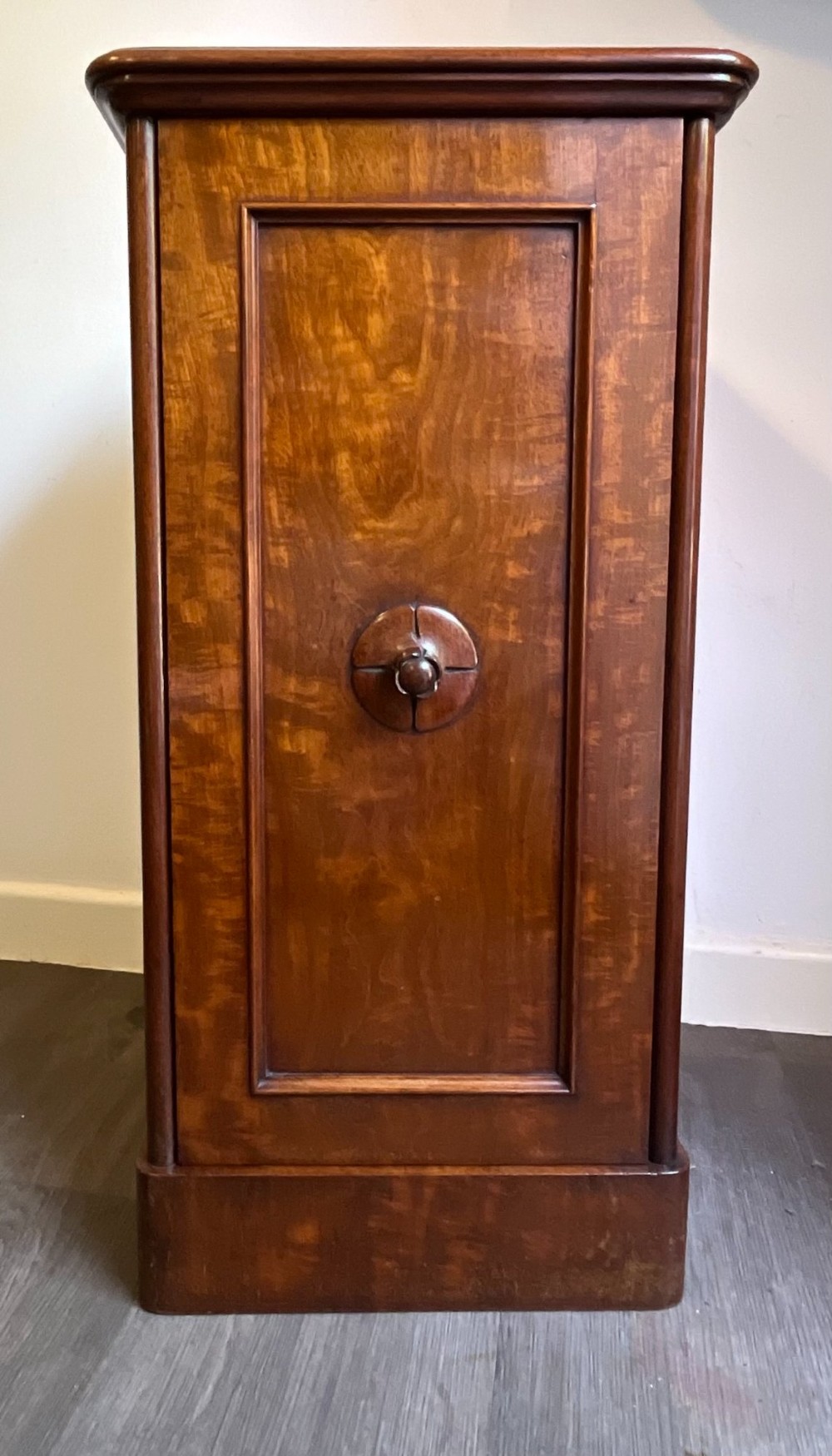 A Victorian warm brown timber pot cupboard featuring a single fielded panel door with a carved central wooden knob and a sturdy plinth base. View VII
