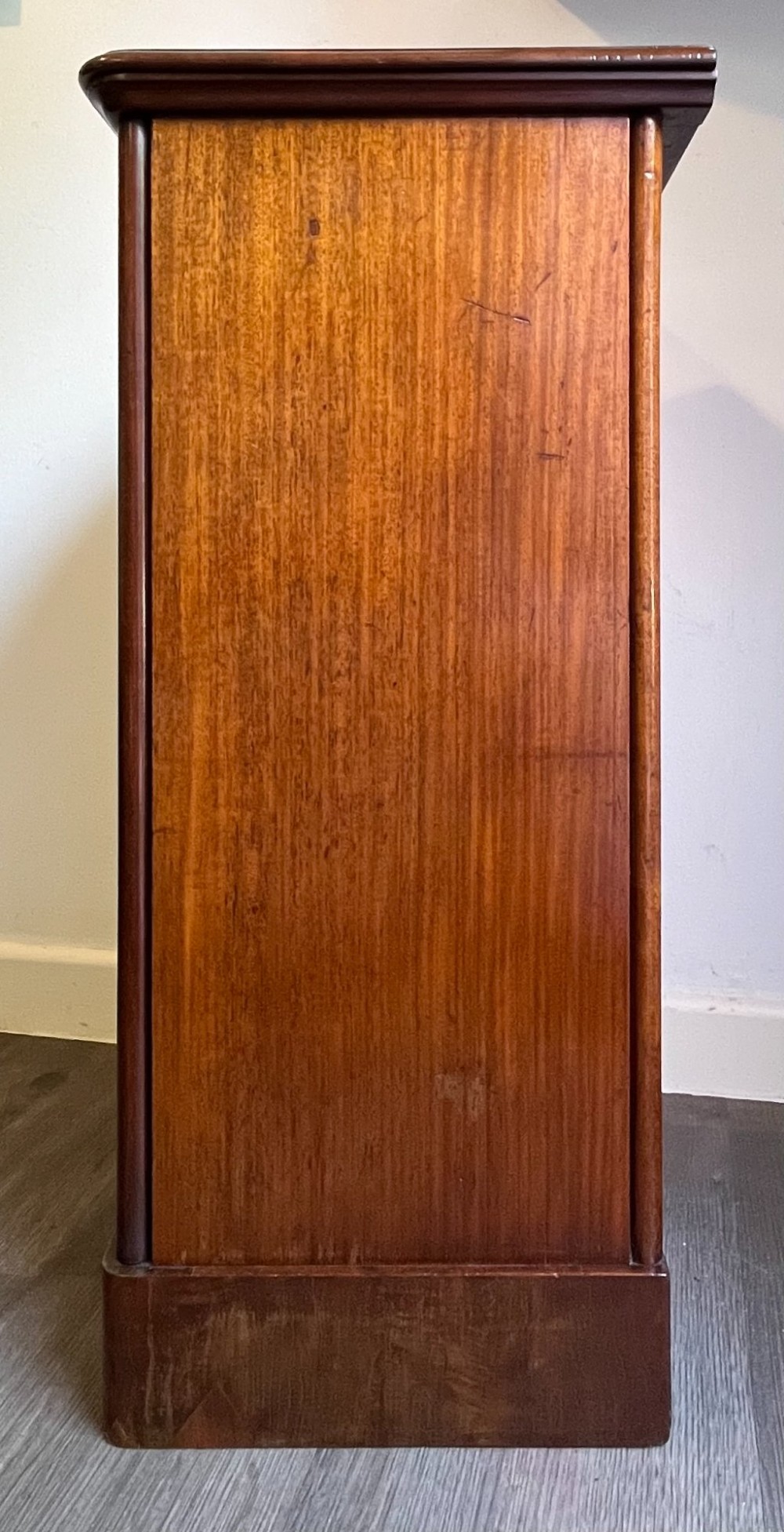 A Victorian warm brown timber pot cupboard featuring a single fielded panel door with a carved central wooden knob and a sturdy plinth base. View VIII