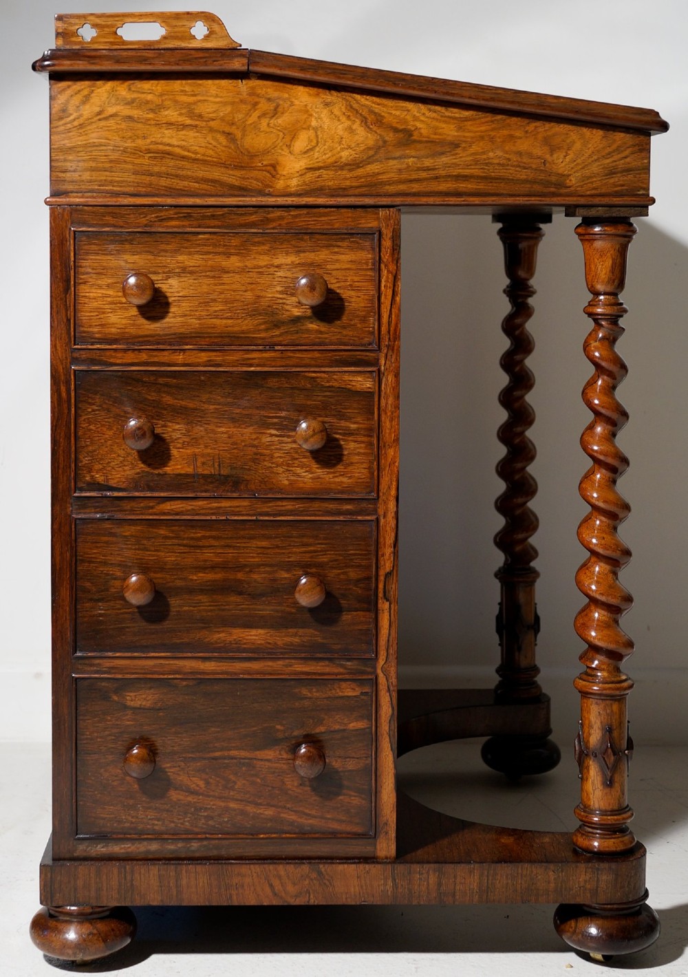An antique dark rosewood Davenport desk featuring a slanted black leather writing surface, pierced gallery top, side drawers, and turned barley twist front columns. View VII