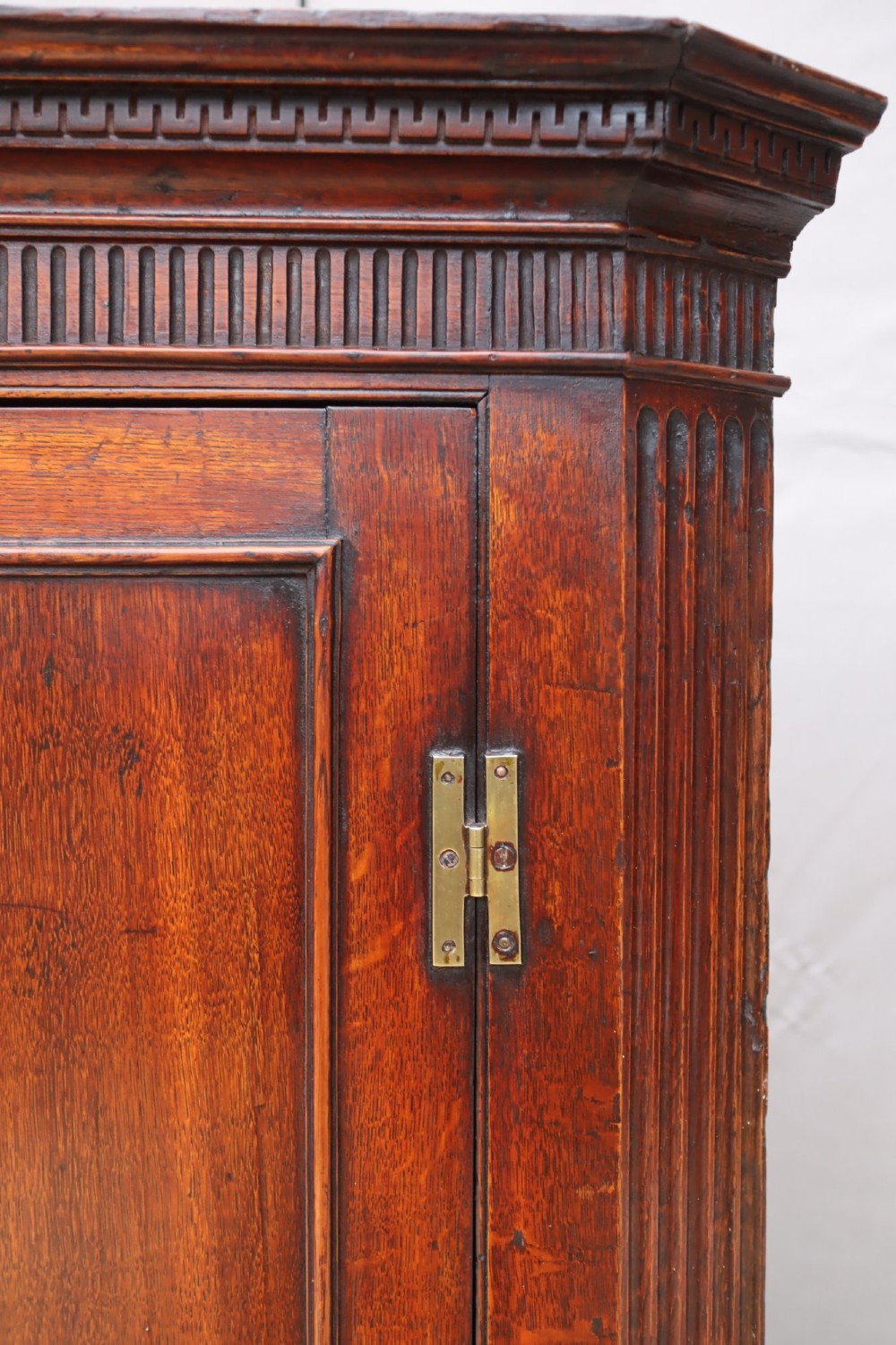 A Georgian mahogany corner cupboard with a single door featuring a central oval starburst inlay and exposed brass H-hinges. View II