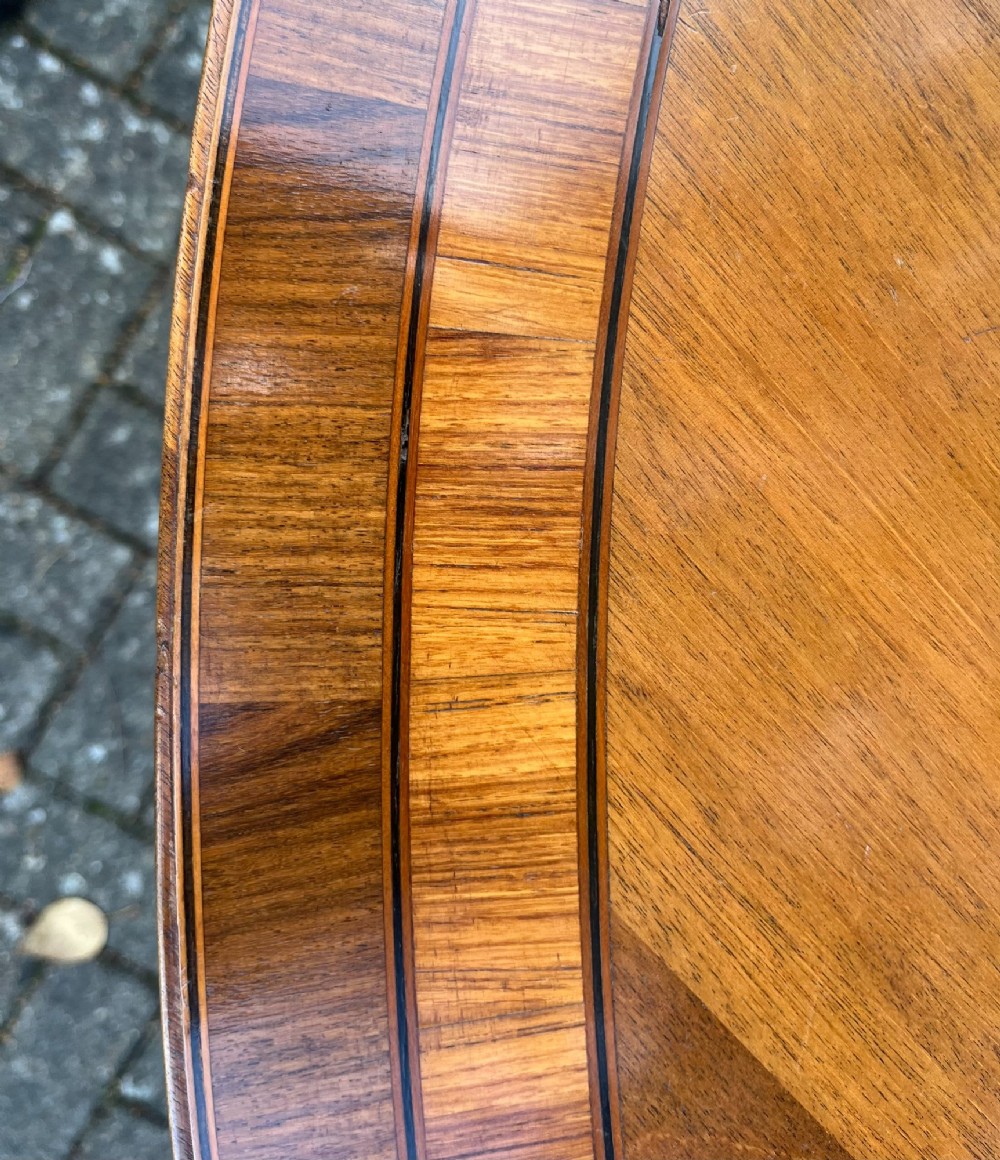 An antique wood tilt-top dining table displaying a circular crossbanded top with inlaid border on a central pedestal base. View IV