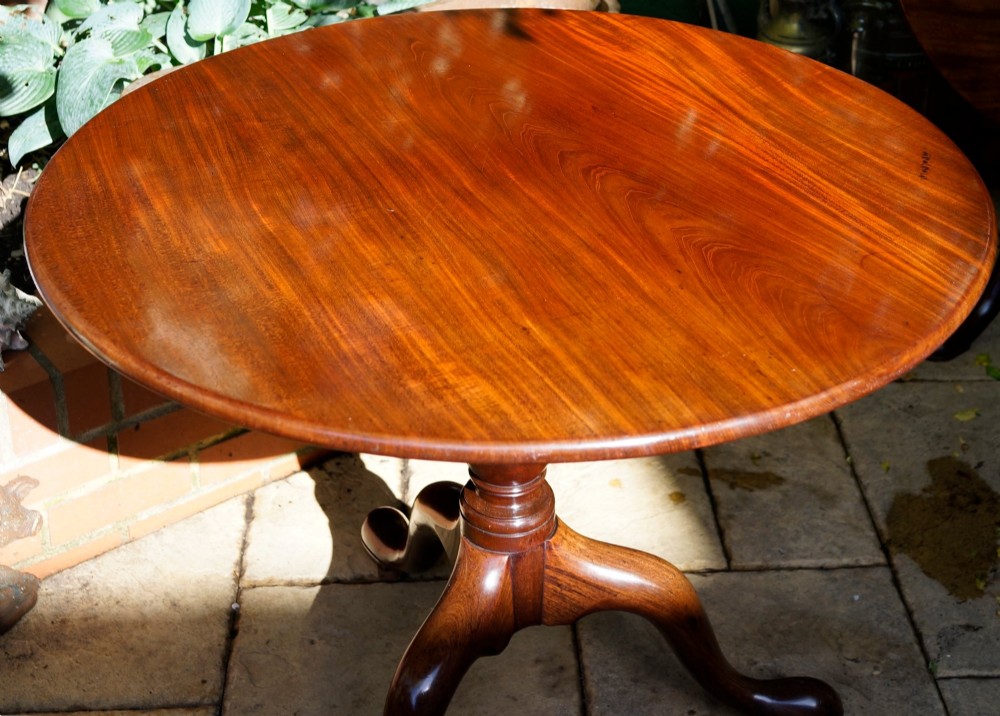 A circular mahogany tripod table featuring a turned baluster stem supported by three cabriole legs. View VI