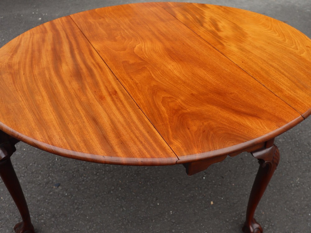 An oval mahogany drop-leaf dining table supported by carved cabriole legs ending in ball-and-claw feet. View IV