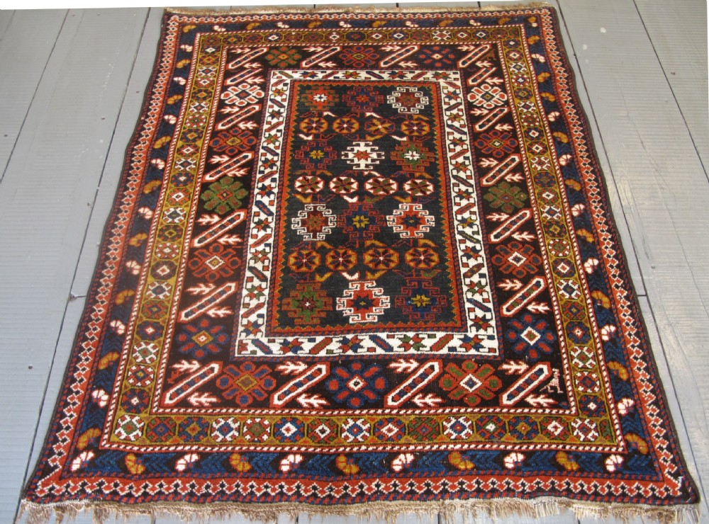 An antique hand-knotted Caucasian Chi-Chi wool area rug featuring intricate geometric motifs and a signature diagonal bar border in navy blue, red, mustard, and green tones. View II