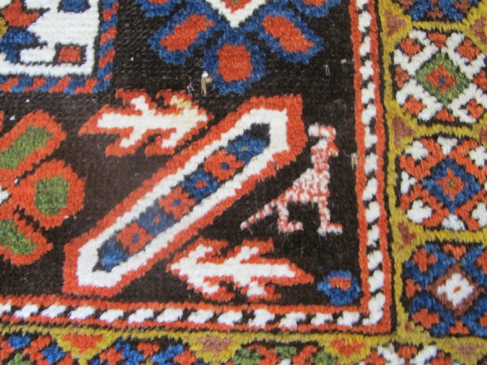 An antique hand-knotted Caucasian Chi-Chi wool area rug featuring intricate geometric motifs and a signature diagonal bar border in navy blue, red, mustard, and green tones. View IV