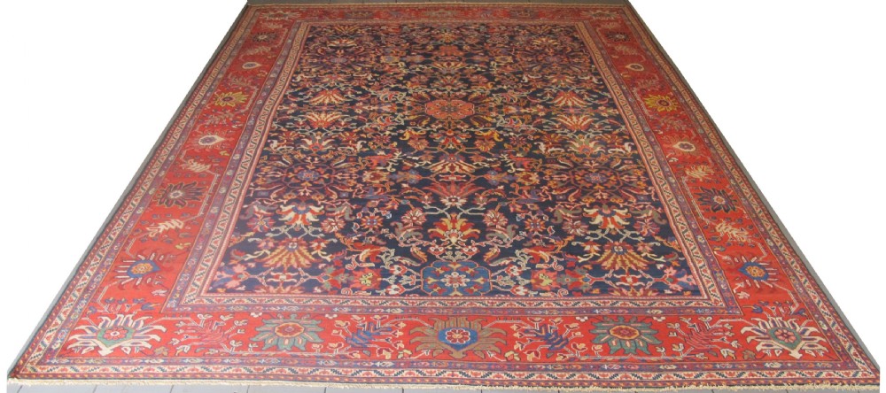 Large rectangular hand-knotted Persian Sultanabad carpet featuring a dark navy floral central field surrounded by a wide terracotta red palmette border.