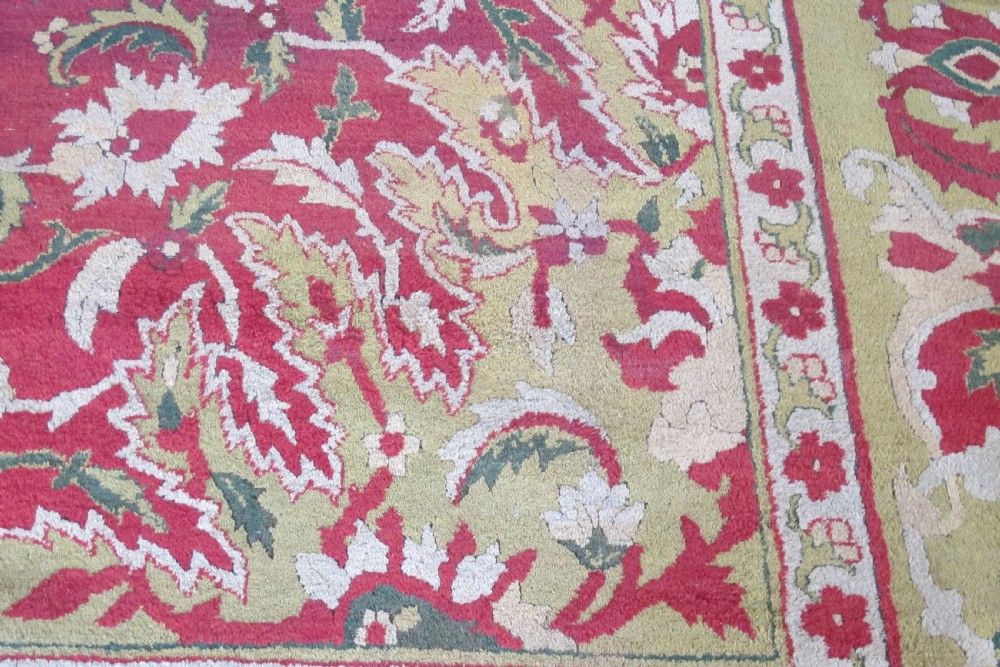 A large hand-knotted wool Amritsar carpet featuring a crimson red field decorated with olive green, cream, and pink floral vine arabesques. View III