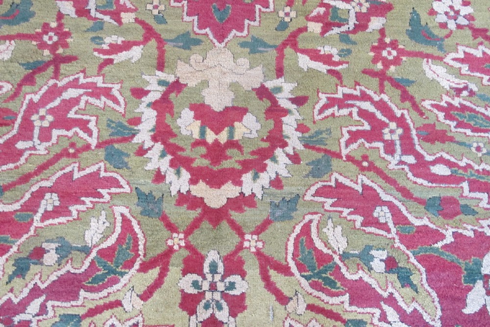A large hand-knotted wool Amritsar carpet featuring a crimson red field decorated with olive green, cream, and pink floral vine arabesques. View IV