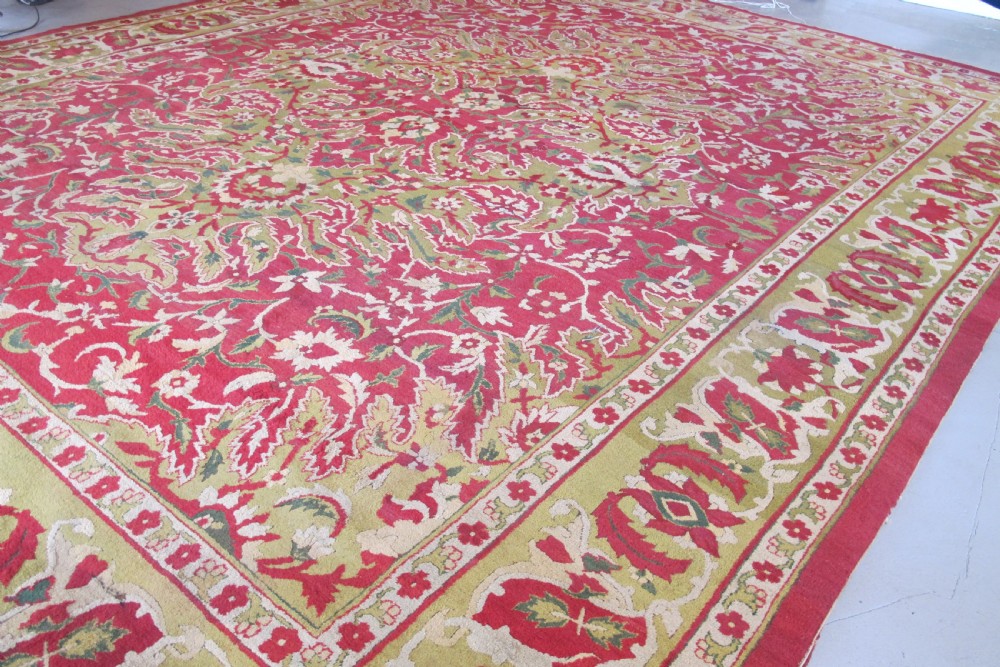 A large hand-knotted wool Amritsar carpet featuring a crimson red field decorated with olive green, cream, and pink floral vine arabesques. View VI