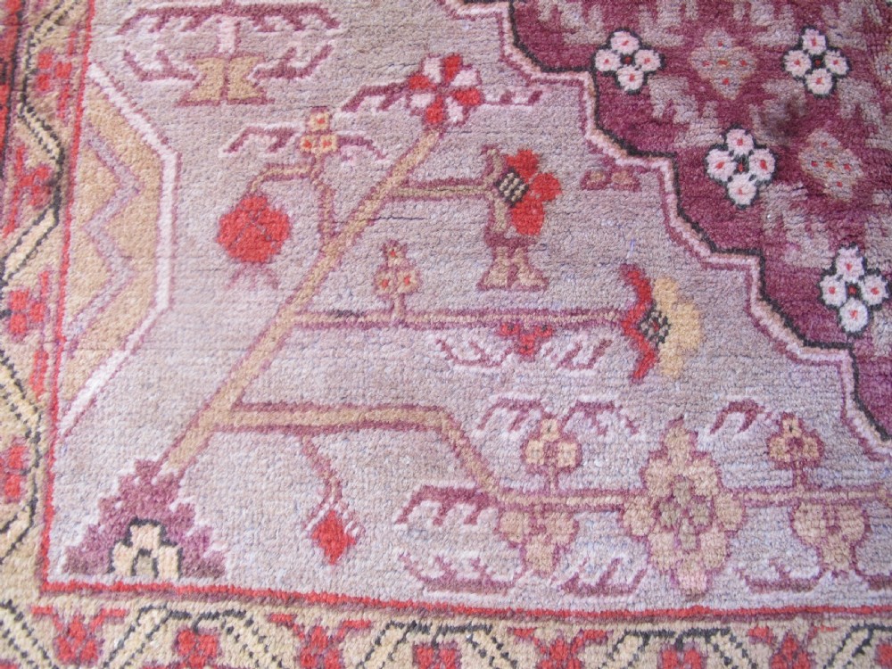 A hand-knotted antique Khotan wool carpet featuring muted rose, terracotta, and beige tones with a geometric lattice pattern and detailed border. View II