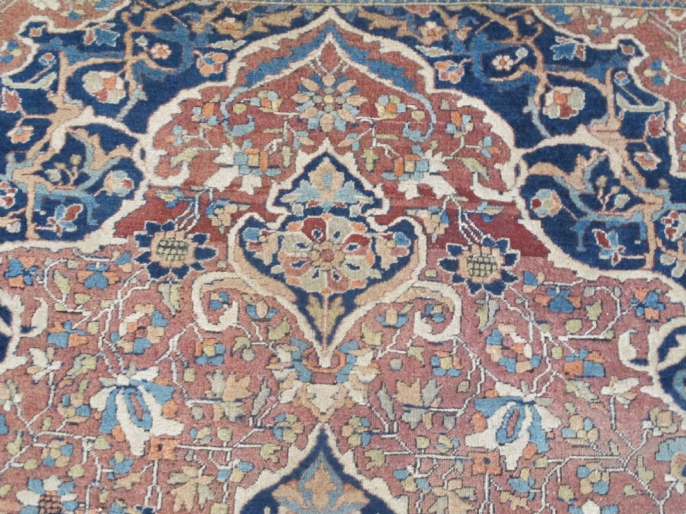 An antique Persian Mohtasham Kashan hand-knotted wool rug featuring a central floral medallion on a terracotta field with a broad navy blue border. View II