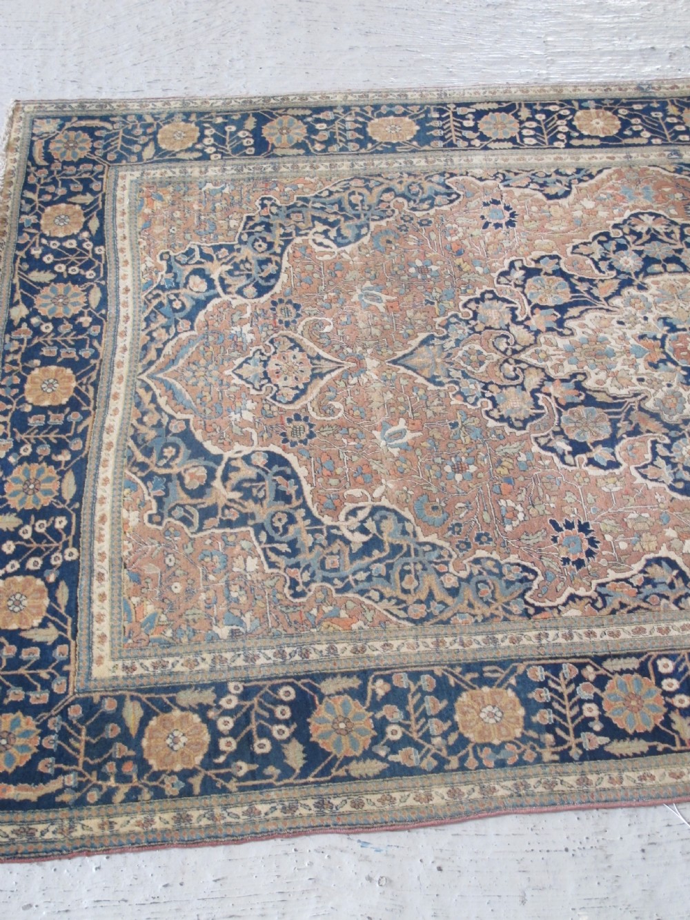 An antique Persian Mohtasham Kashan hand-knotted wool rug featuring a central floral medallion on a terracotta field with a broad navy blue border. View III