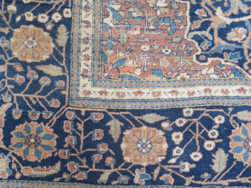An antique Persian Mohtasham Kashan hand-knotted wool rug featuring a central floral medallion on a terracotta field with a broad navy blue border. View VI