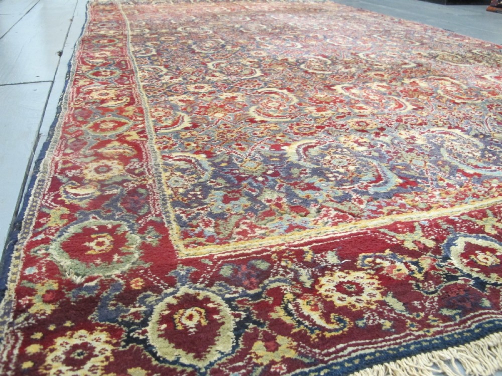 A large late 19th-century hand-knotted Agra wool carpet featuring intricate scrolling botanical motifs in crimson red, blue, and cream with a wide decorative border. View II