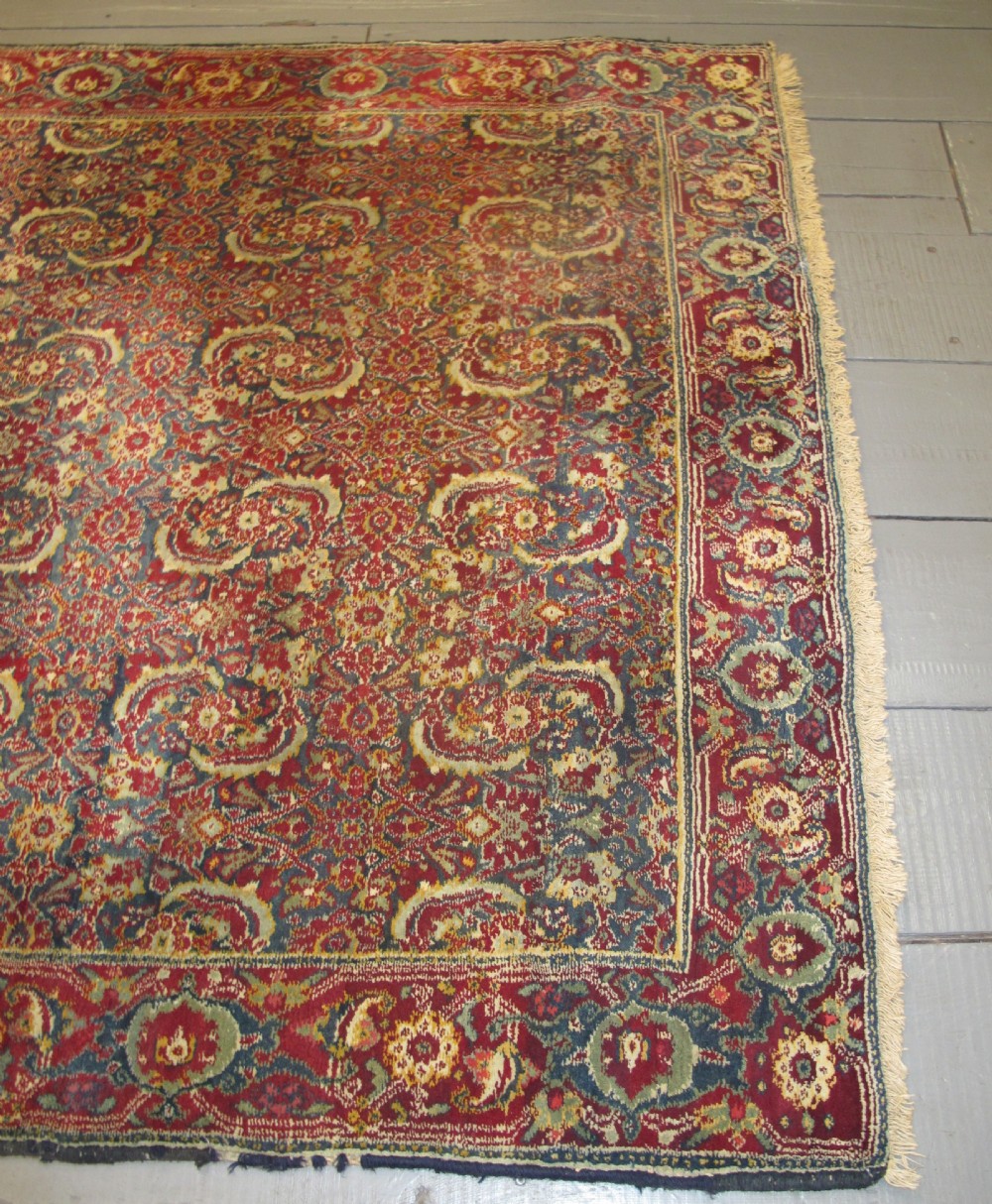 A large late 19th-century hand-knotted Agra wool carpet featuring intricate scrolling botanical motifs in crimson red, blue, and cream with a wide decorative border. View VI