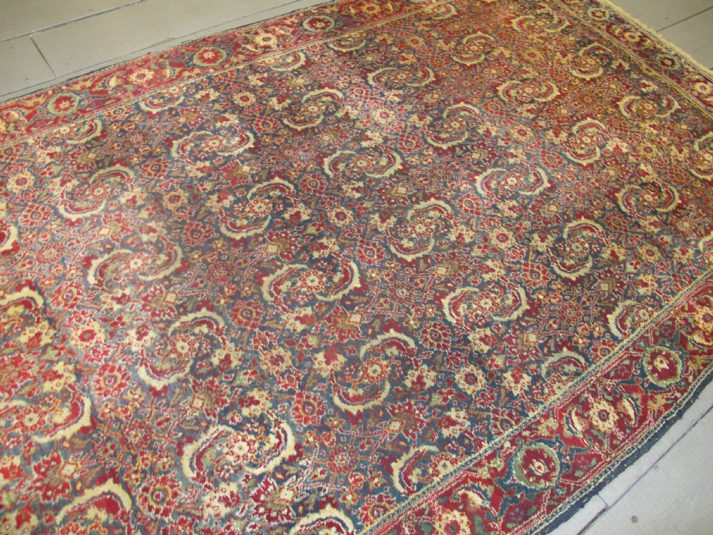 A large late 19th-century hand-knotted Agra wool carpet featuring intricate scrolling botanical motifs in crimson red, blue, and cream with a wide decorative border. View VIII