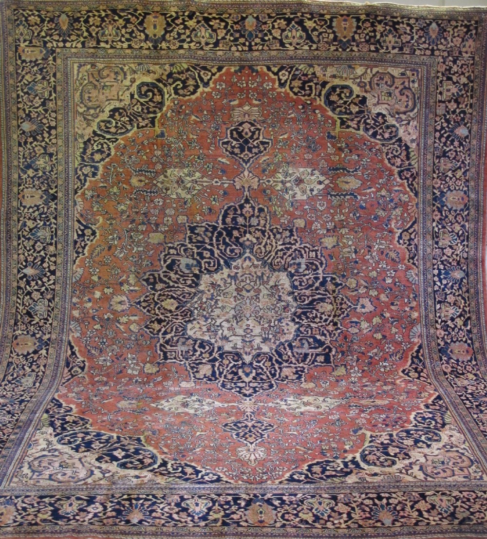 A large hand-knotted antique Persian Fereghan carpet featuring a central navy blue and ivory medallion framed by intricate floral patterns on a terracotta red field with decorative navy borders. View III