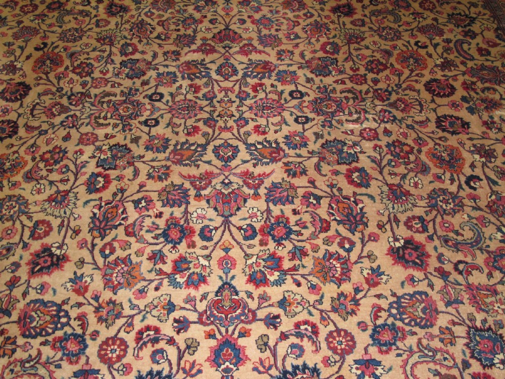A large antique Persian wool carpet featuring a dense all-over floral pattern on a cream field framed by a wide red decorative border. View III