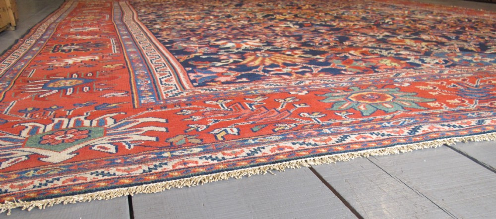 Large rectangular hand-knotted Persian Sultanabad carpet featuring a dark navy floral central field surrounded by a wide terracotta red palmette border. View VIII