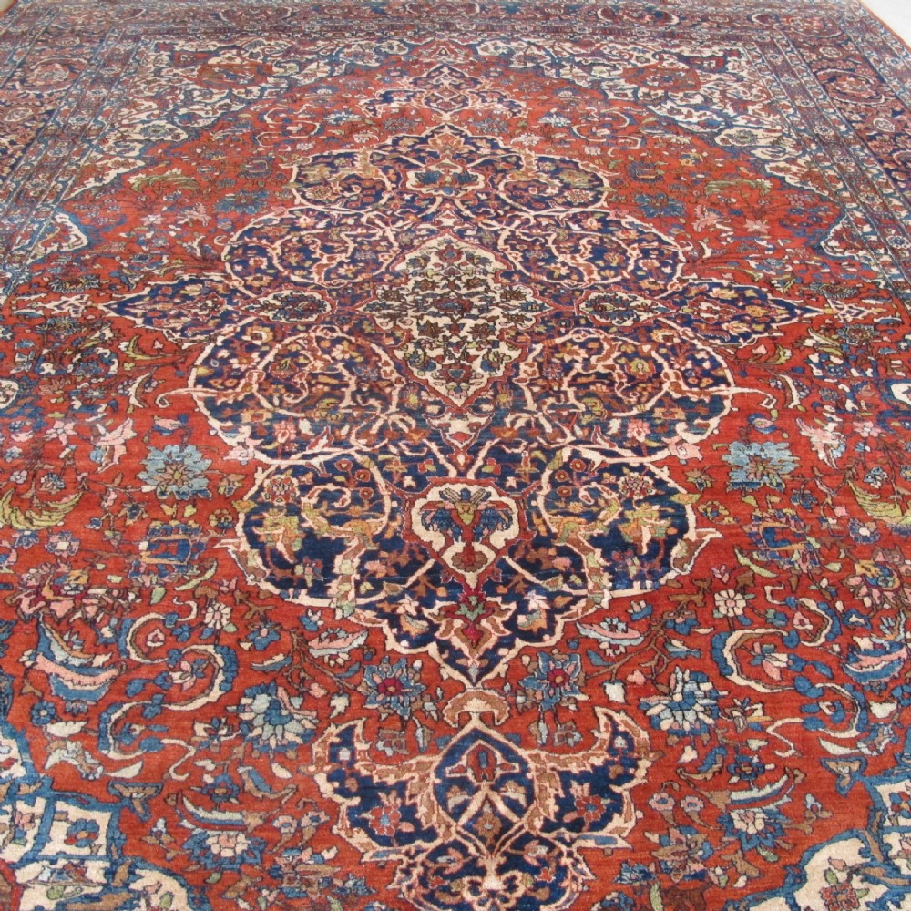 A large hand-knotted Persian Isfahan wool rug featuring a elaborate central medallion with indigo and cream arabesque floral patterns on a deep red field. View II