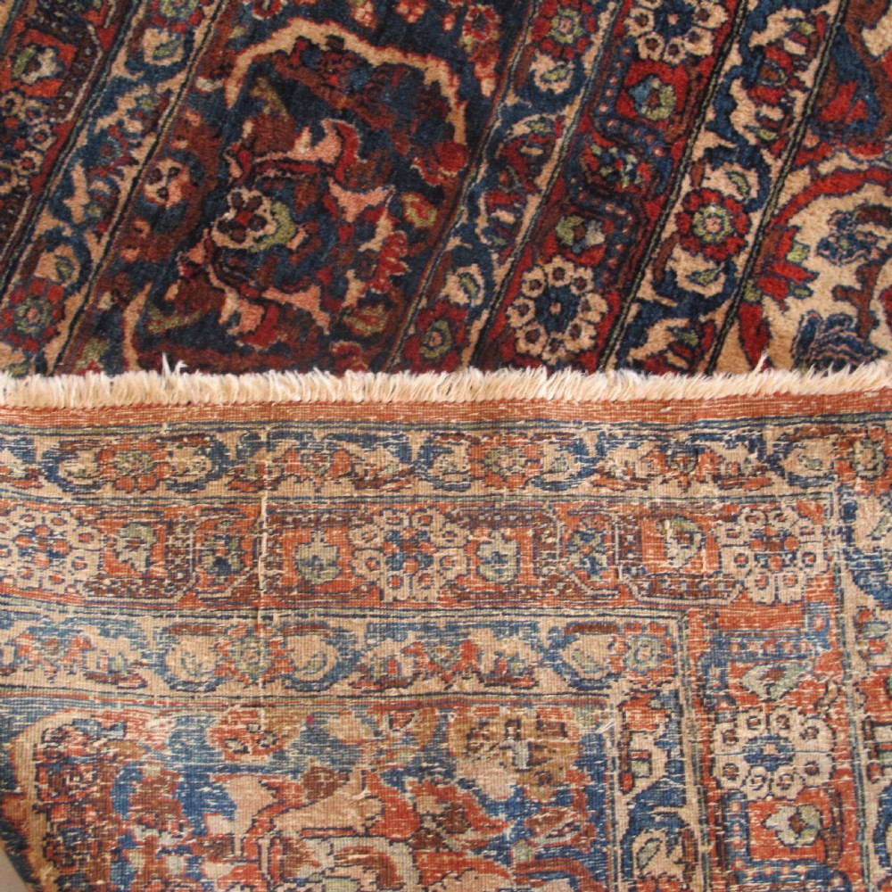 A large hand-knotted Persian Isfahan wool rug featuring a elaborate central medallion with indigo and cream arabesque floral patterns on a deep red field. View V