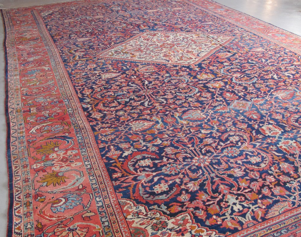 A large palace-sized antique Persian Sultanabad wool carpet featuring a deep navy blue central field, an ivory diamond medallion, intricate floral arabesques, and a broad terracotta border. View II