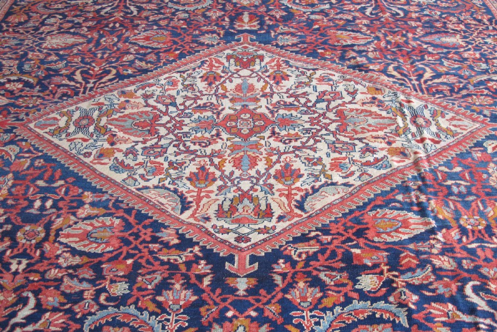A large palace-sized antique Persian Sultanabad wool carpet featuring a deep navy blue central field, an ivory diamond medallion, intricate floral arabesques, and a broad terracotta border. View III