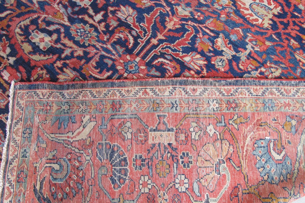 A large palace-sized antique Persian Sultanabad wool carpet featuring a deep navy blue central field, an ivory diamond medallion, intricate floral arabesques, and a broad terracotta border. View IV