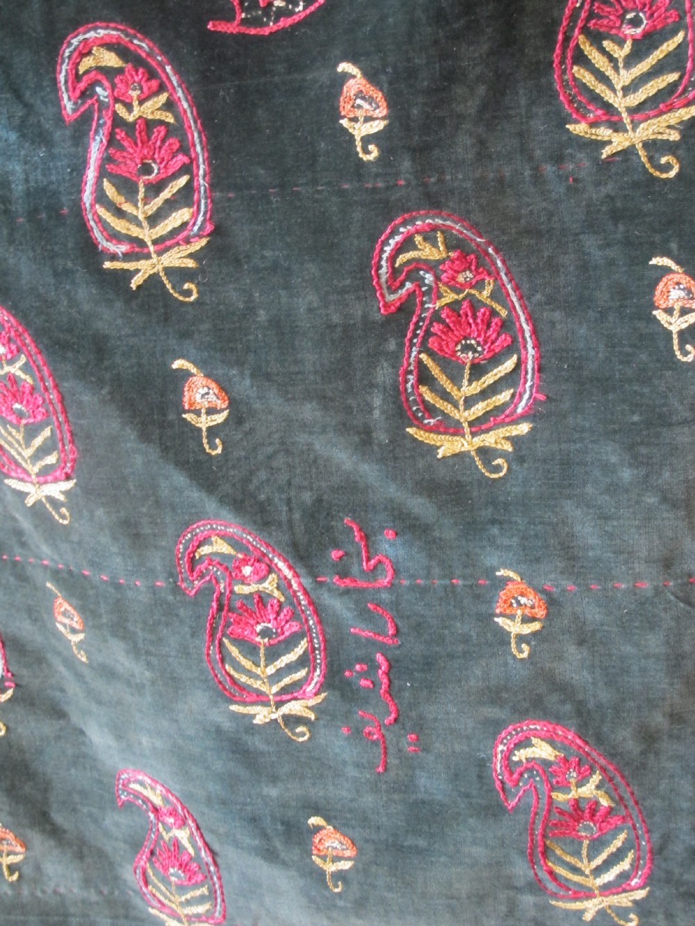 A large rectangular dark green velvet panel featuring intricate pink and gold embroidered floral medallions and boteh patterns. View V