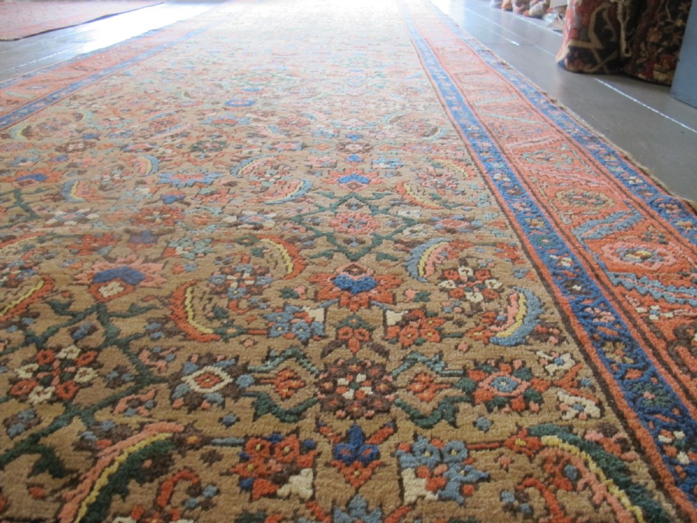 A long hand-knotted antique North-West Persian gallery carpet featuring detailed floral patterns on a camel field with terracotta borders. View VII