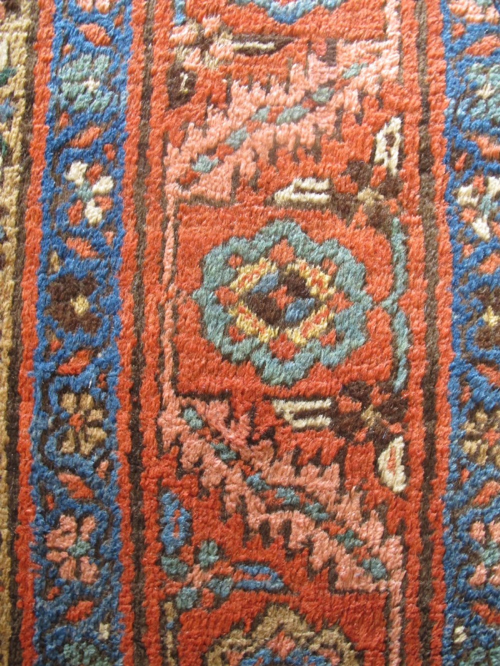 A long hand-knotted antique North-West Persian gallery carpet featuring detailed floral patterns on a camel field with terracotta borders. View IX