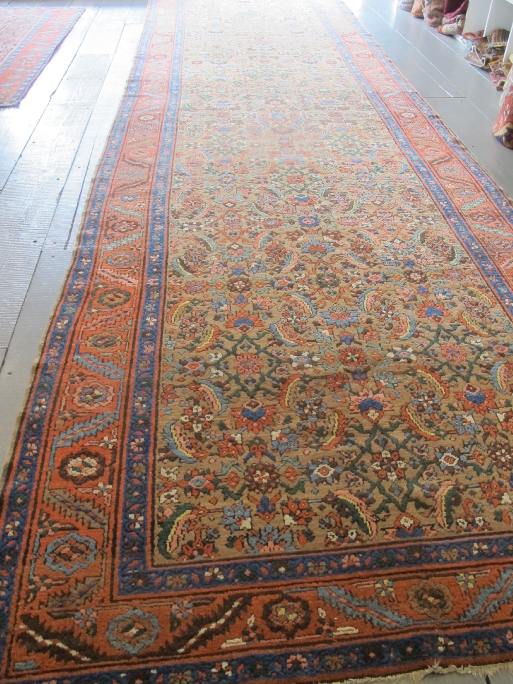 A long hand-knotted antique North-West Persian gallery carpet featuring detailed floral patterns on a camel field with terracotta borders. View XII