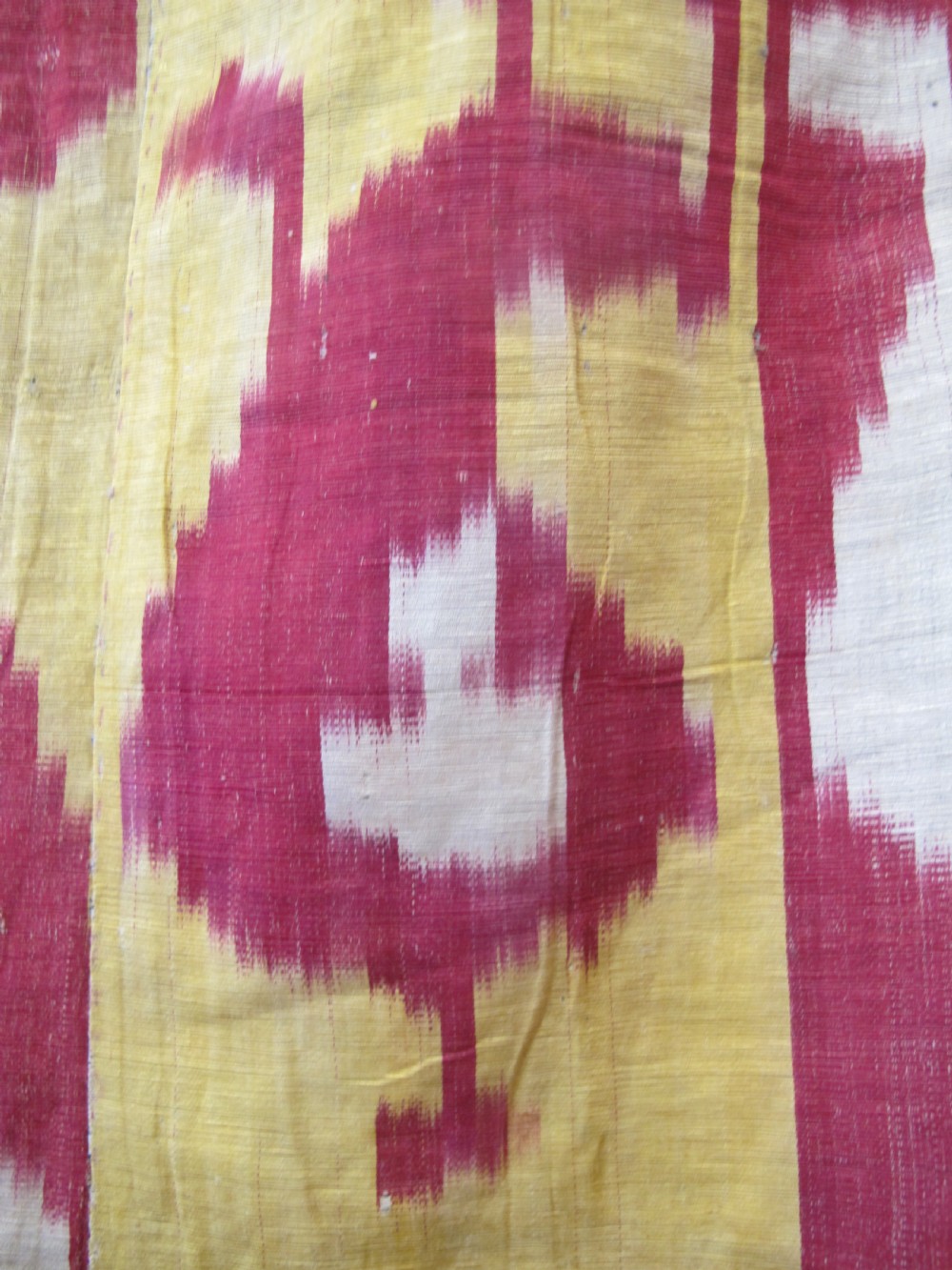 An antique Uzbek handwoven silk ikat panel with repeating vertical geometric and abstract cloud motifs in crimson, yellow, and off-white. View IV
