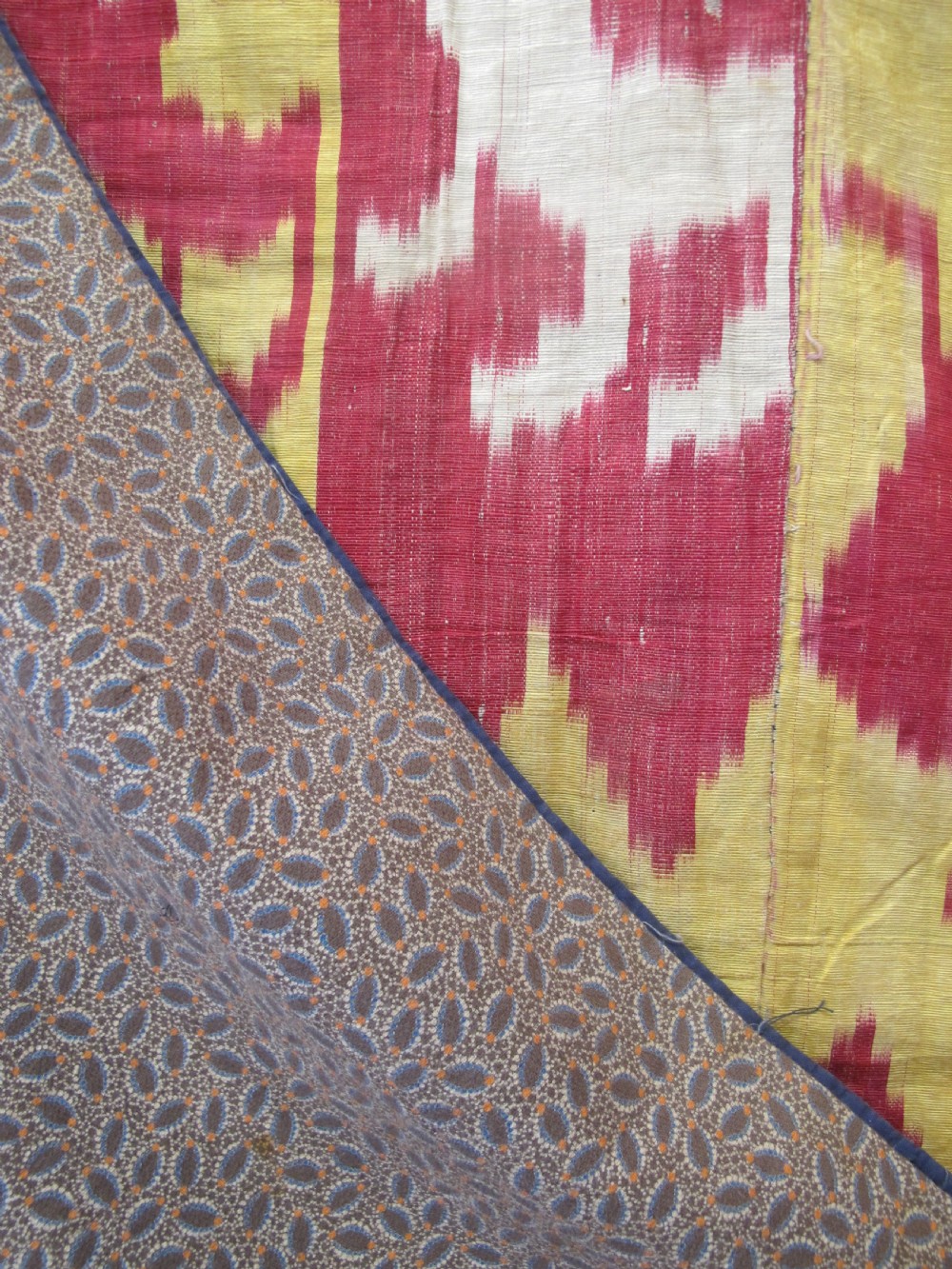 An antique Uzbek handwoven silk ikat panel with repeating vertical geometric and abstract cloud motifs in crimson, yellow, and off-white. View V