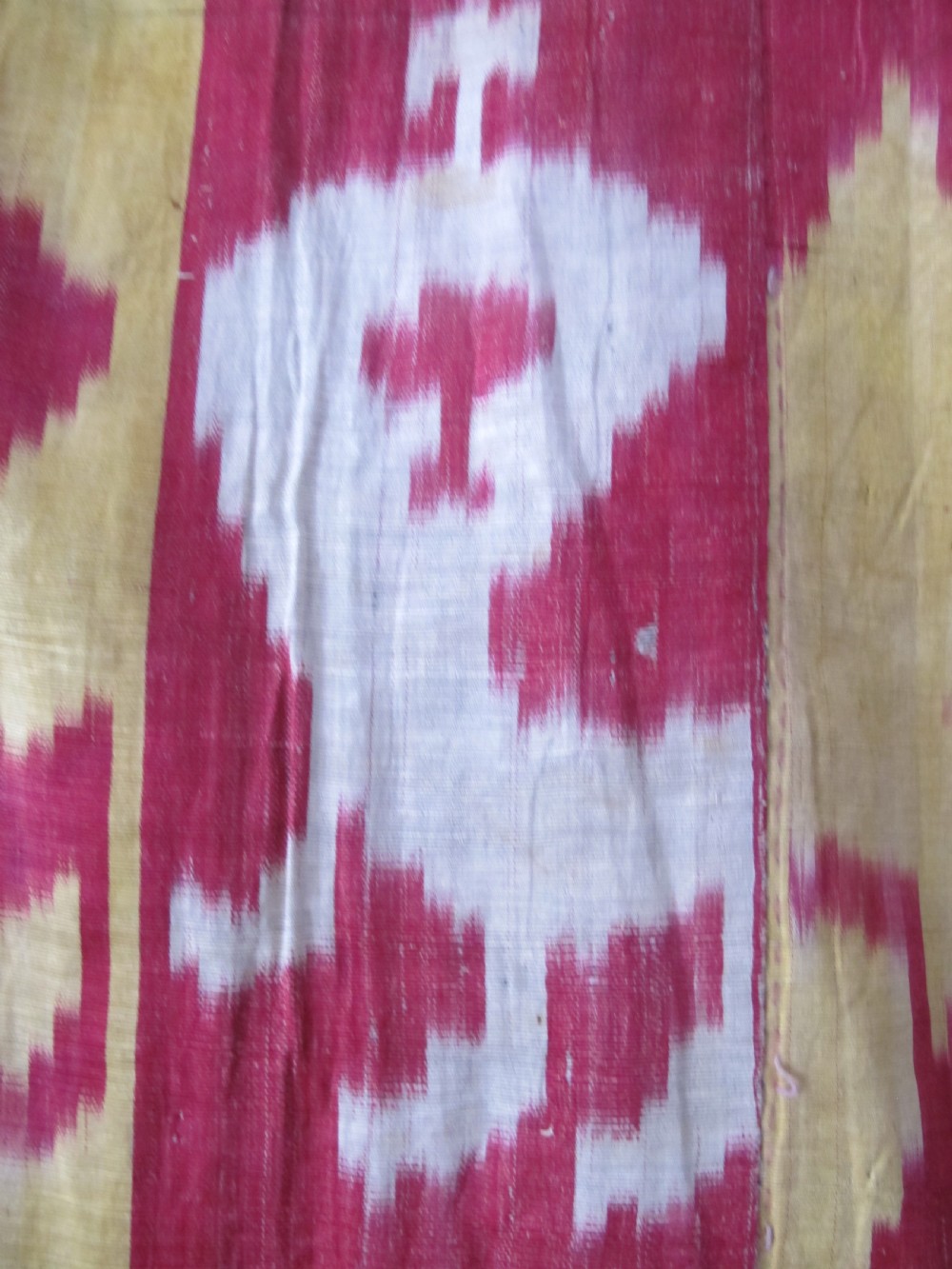 An antique Uzbek handwoven silk ikat panel with repeating vertical geometric and abstract cloud motifs in crimson, yellow, and off-white. View VI