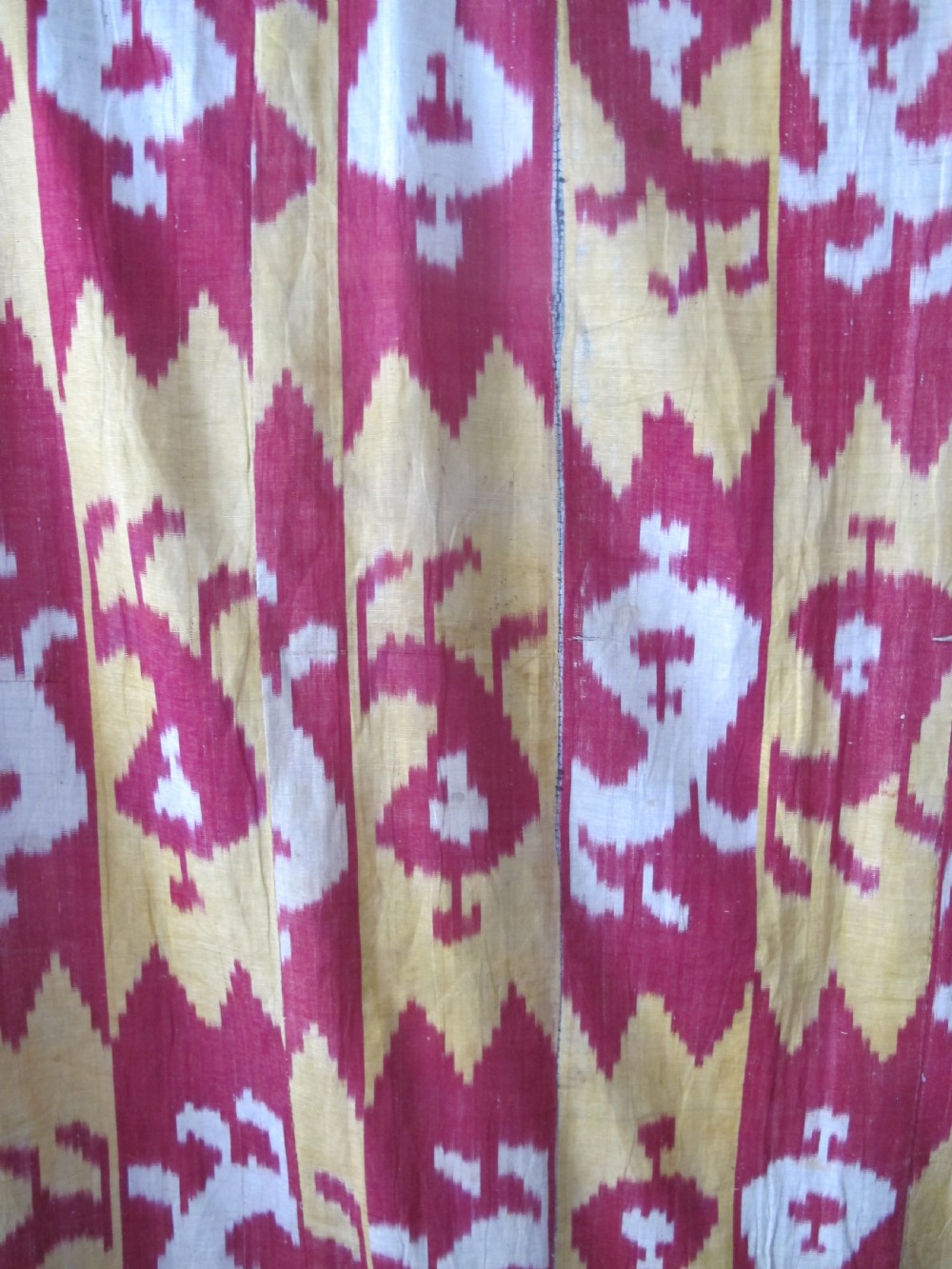 An antique Uzbek handwoven silk ikat panel with repeating vertical geometric and abstract cloud motifs in crimson, yellow, and off-white. View VIII