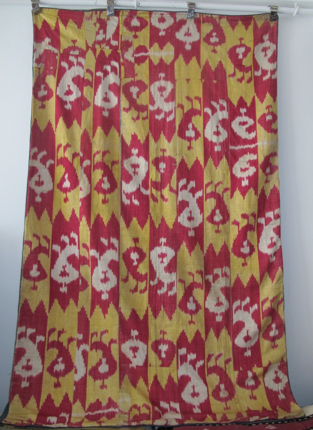 An antique Uzbek handwoven silk ikat panel with repeating vertical geometric and abstract cloud motifs in crimson, yellow, and off-white. View XI
