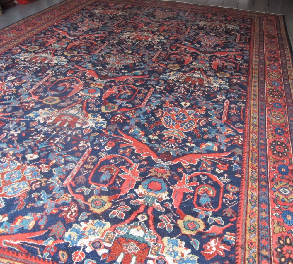 A large hand-knotted antique Persian Mahal carpet featuring a navy blue field filled with terracotta and light blue Mostafi floral patterns and a wide multi-band border.