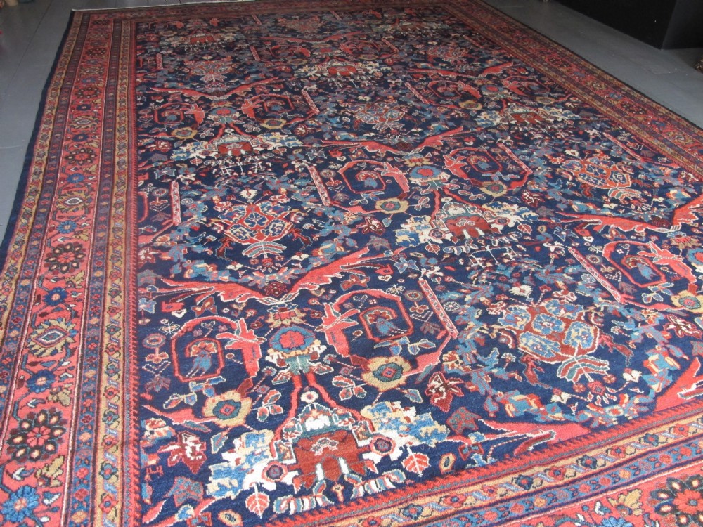 A large hand-knotted antique Persian Mahal carpet featuring a navy blue field filled with terracotta and light blue Mostafi floral patterns and a wide multi-band border. View VI