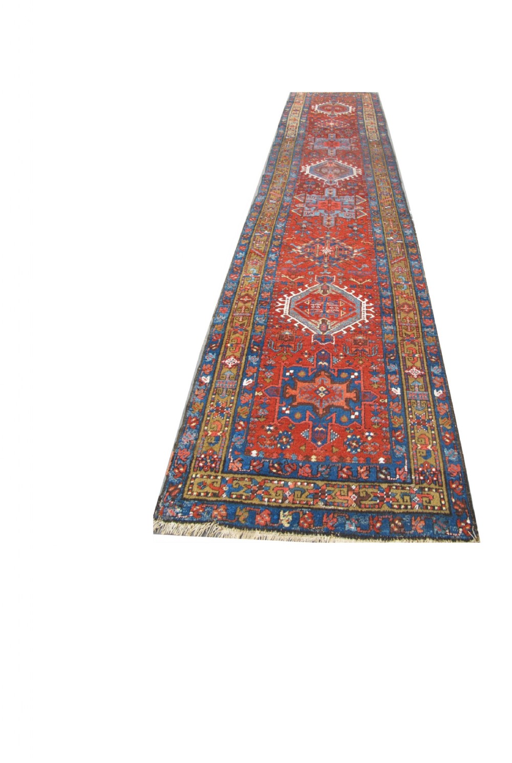 A long hand-knotted Persian Heriz wool runner rug featuring geometric medallions in shades of red, blue, and gold against a red field.